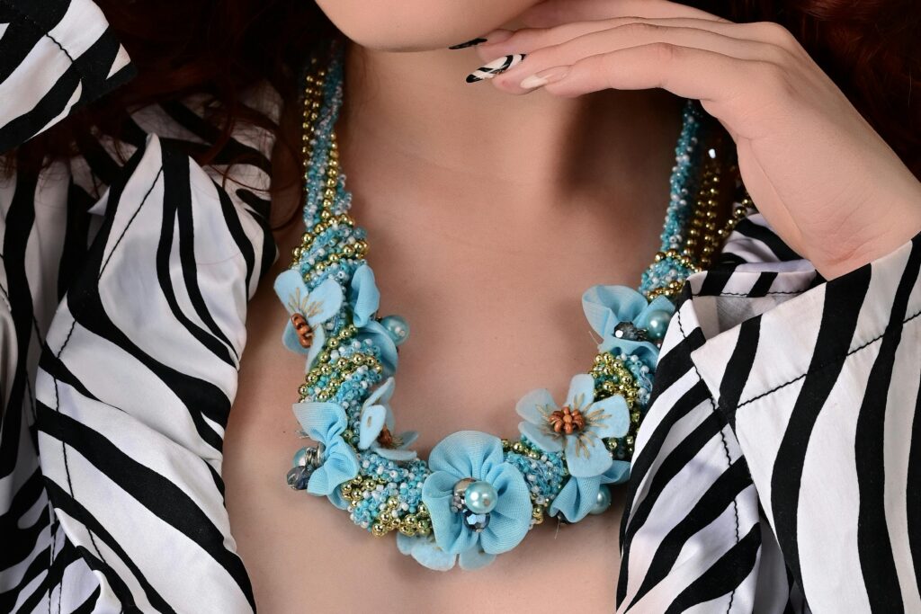 Elegant close-up of a woman showcasing a striking zebra print outfit paired with a floral statement necklace.