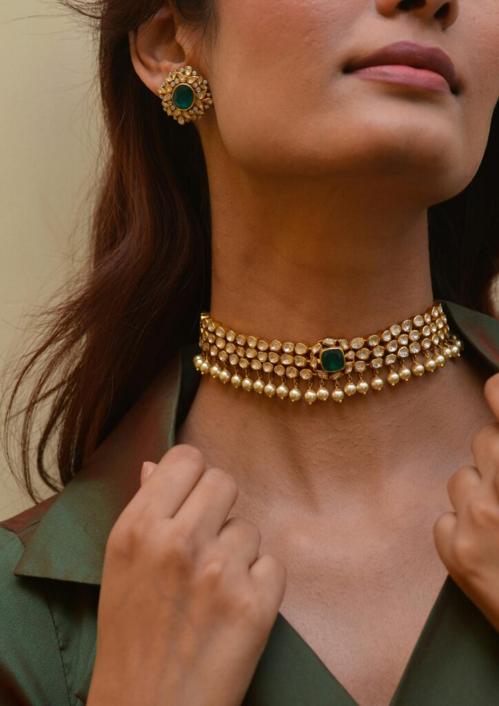 Close-up of a woman wearing a stylish gold and emerald jewelry set.