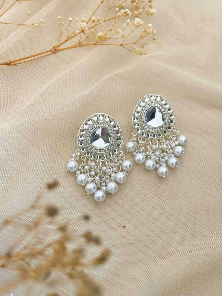 Beautiful silver earrings embellished with pearls on a soft fabric background.