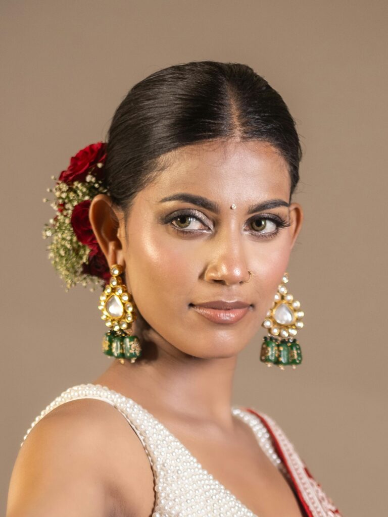Close-up portrait of a woman with traditional jewelry and flower adornment. Captures elegance and cultural beauty.
